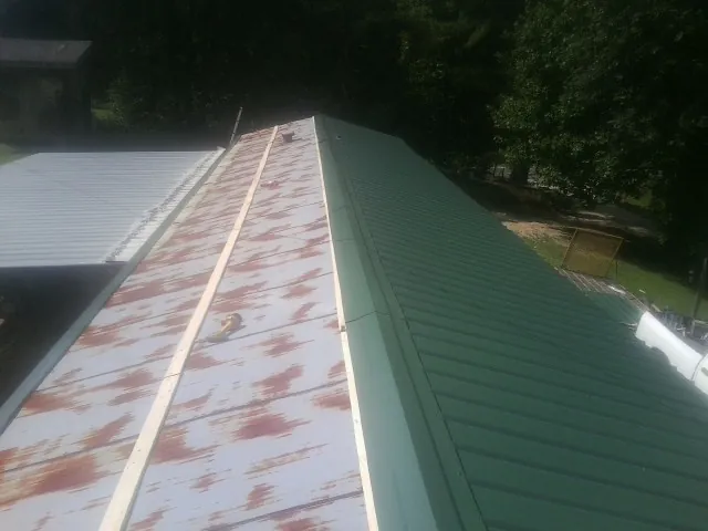 Old rusted panels beside newly installed green metal roofing — Wind Damage Roof Repair by Roofing Brothers in Oakville