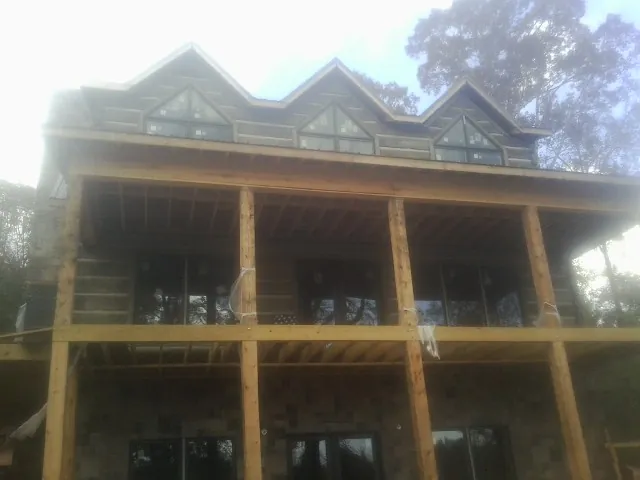 Dormers and porch framing on a large log home under construction — Roof Coating work by our crew in Oakville