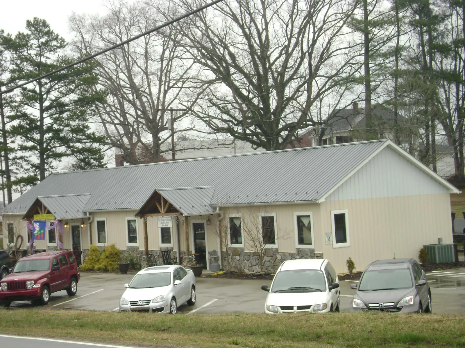 Gray metal roof with timber entry brackets on a small commercial building in Oakville